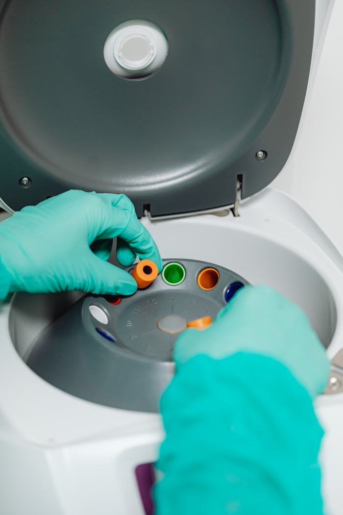 team-04 Hands in gloves adjusting samples in a laboratory centrifuge.