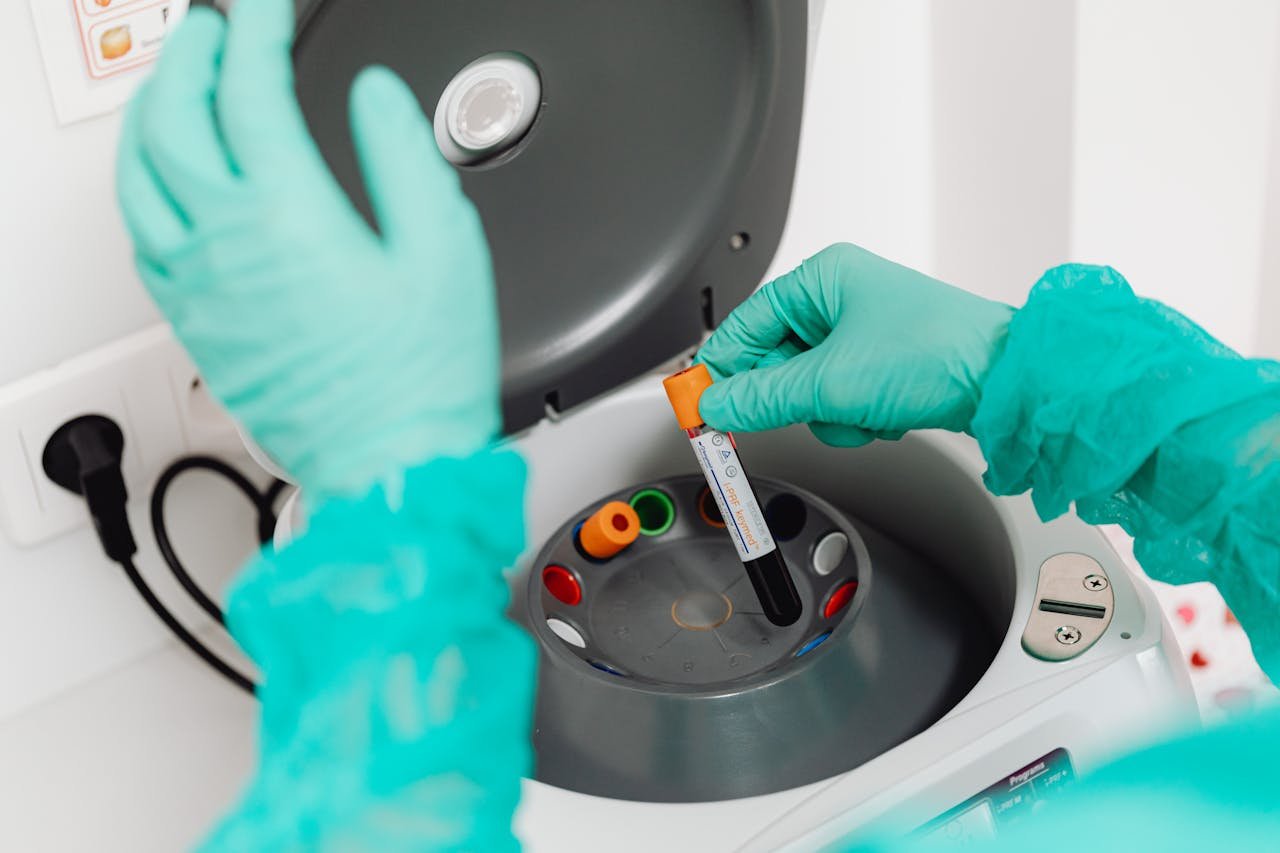 team-01 A lab technician wearing gloves uses a centrifuge for blood analysis in a modern laboratory setting.