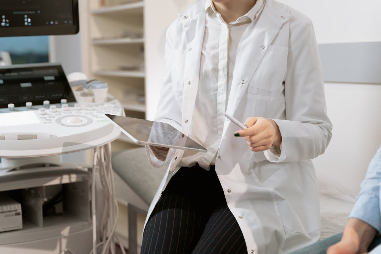 who-we-are Doctor holding a tablet in a modern medical office during a patient consultation.