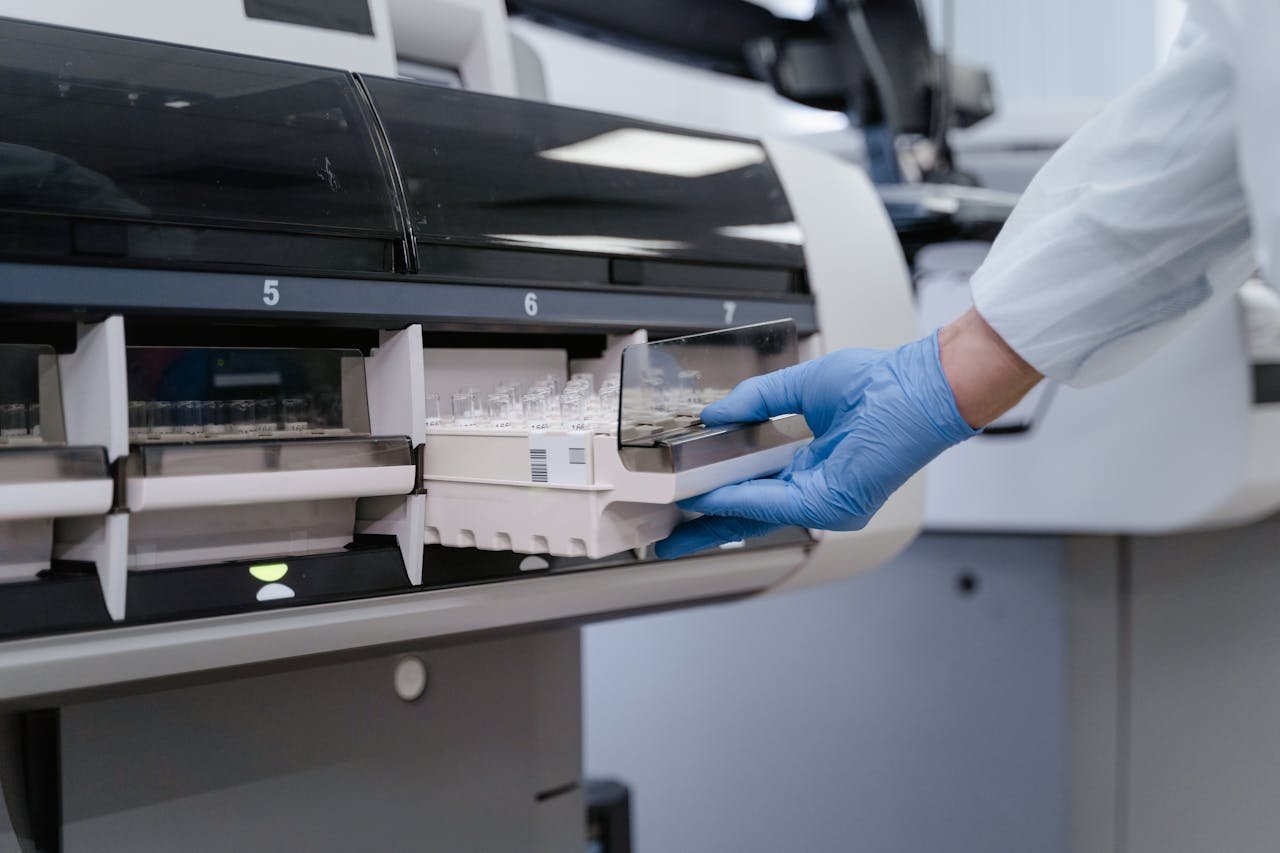 team-02 A lab technician in blue gloves handling samples in a scientific instrument.